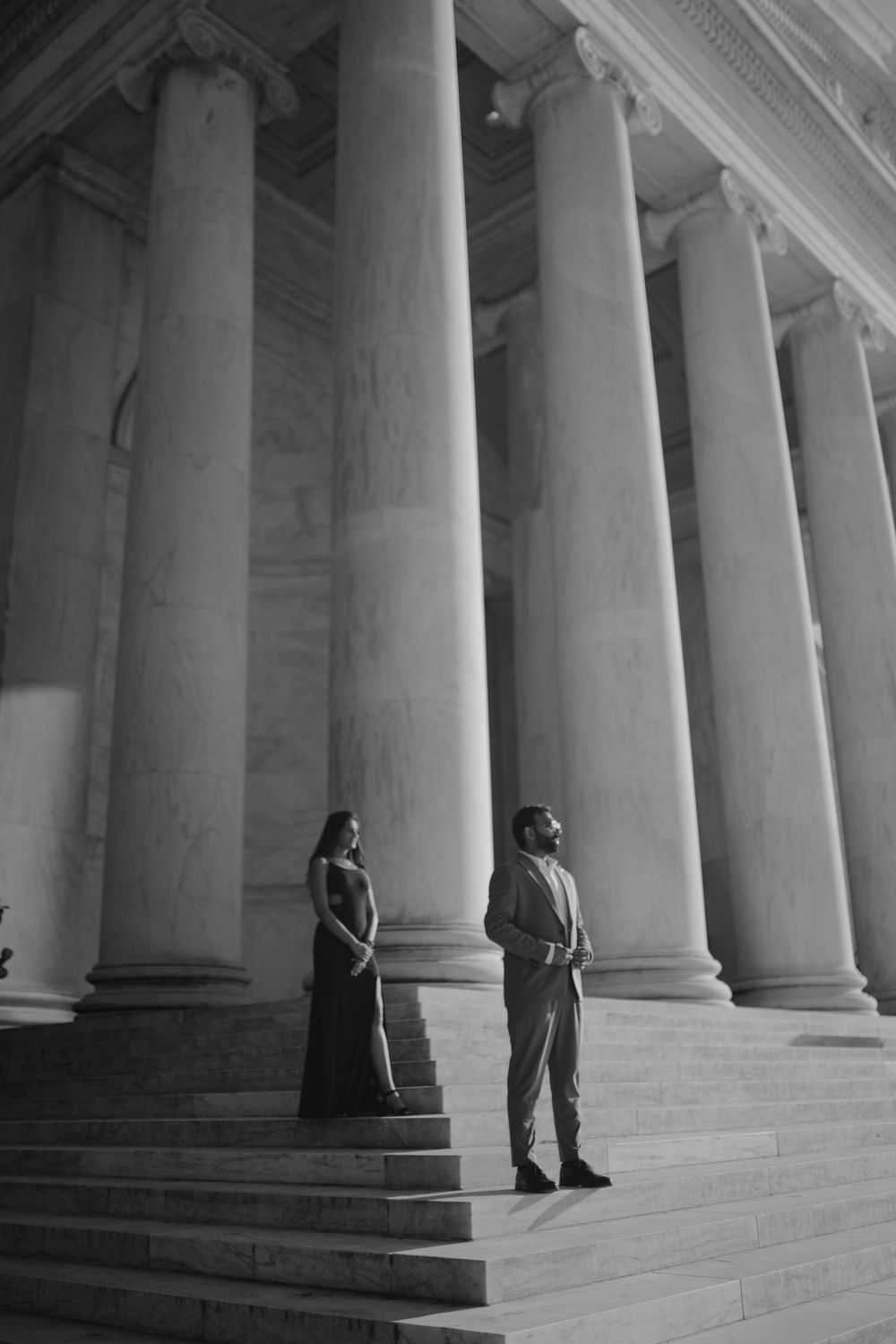 Artistic black and white portrait against towering neoclassical columns and steps.