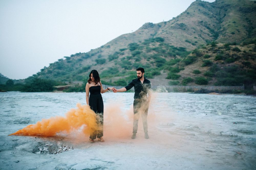 Colorful smoke bombs create dramatic effects as a couple poses by a mountain lake.