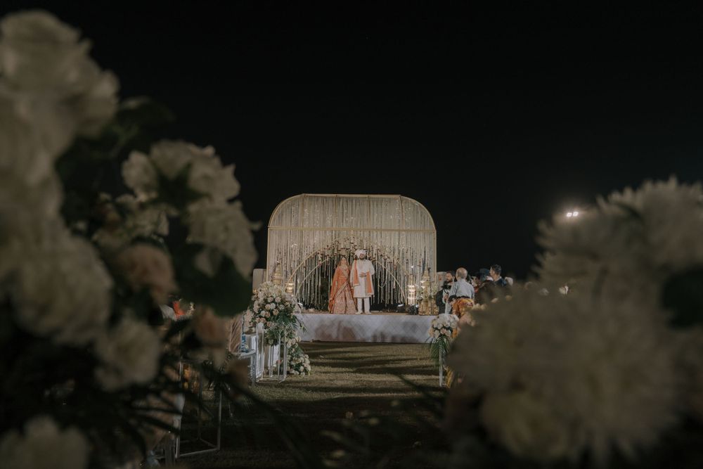 Evening wedding reception setup with elegant decor and ambient lighting under a decorative canopy.
