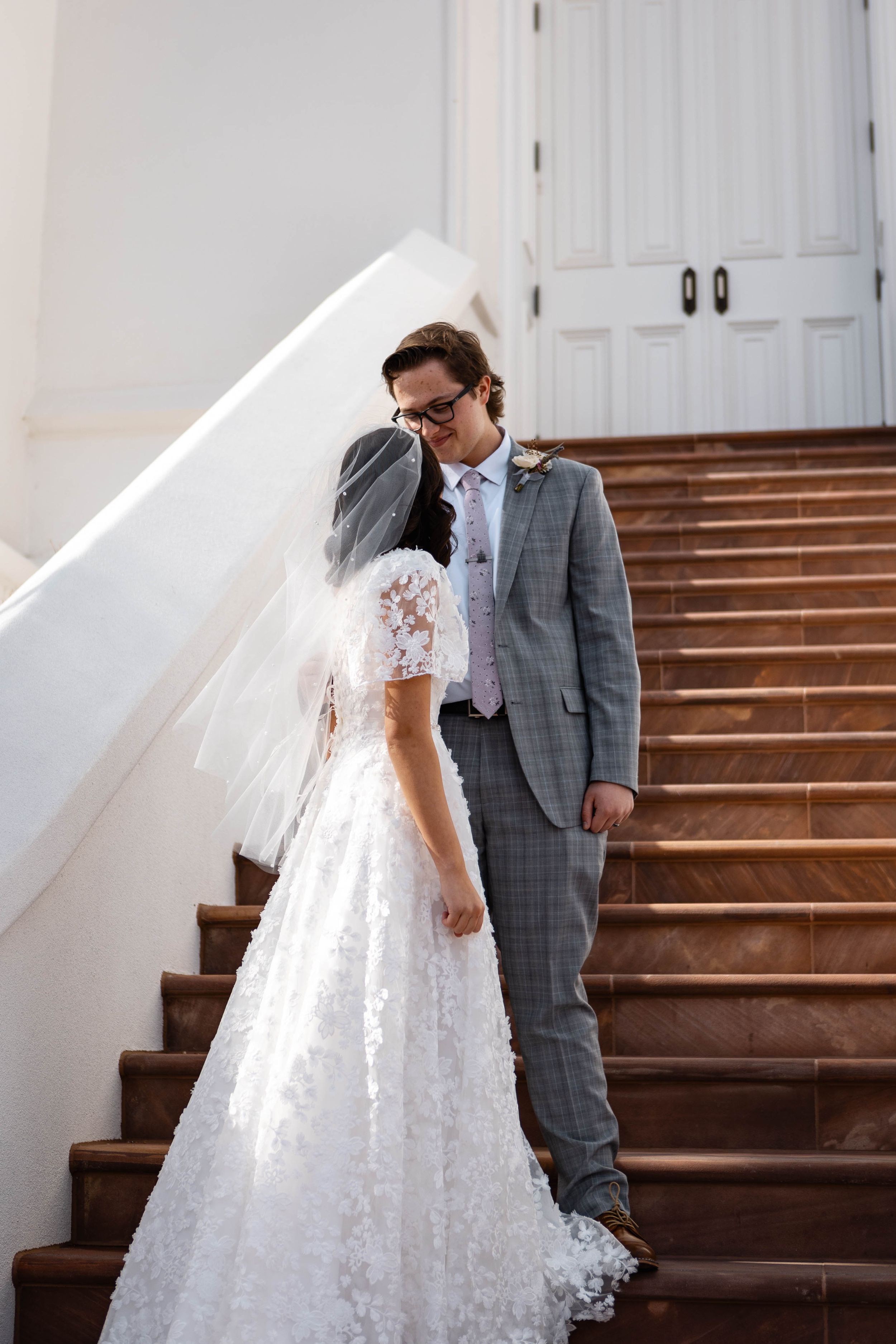 Bride and groom standing one the steps of a LDS temple looking at each other