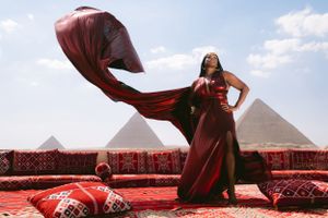 Red dress fabric caught in motion against ancient pyramid backdrop.
