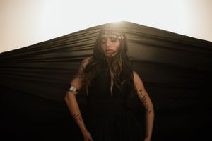Artistic portrait with dramatic lighting showcasing tattoos and dark attire.