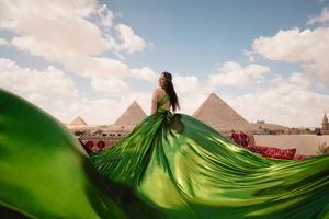Emerald green flowing dress creates dramatic silhouette against Egyptian pyramid landscape.