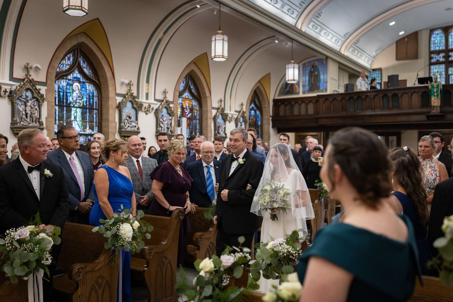 Bride walking down the aisle in a church wedding ceremony surrounded by guests in formal attire.