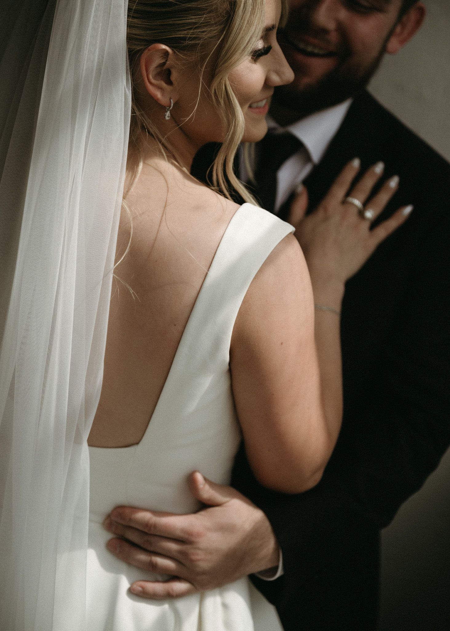 A romantic wedding couple embraces intimately in a series of candid black and white photos against a light background.