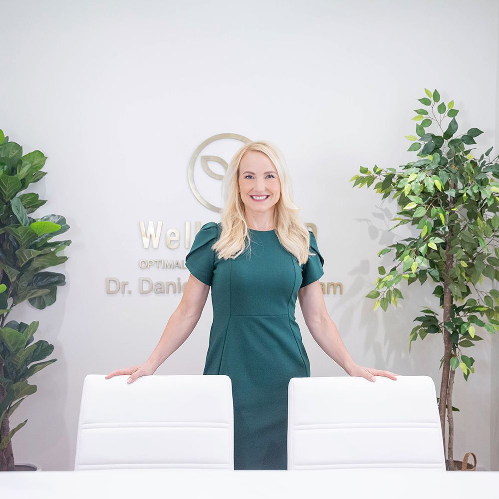 Healthcare professional in green dress stands confidently in modern medical office with plants.