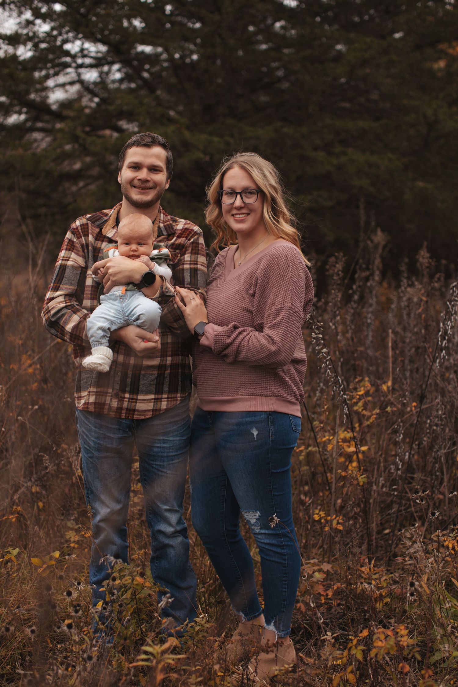 Family portrait in autumn setting with rustic fall foliage in background.