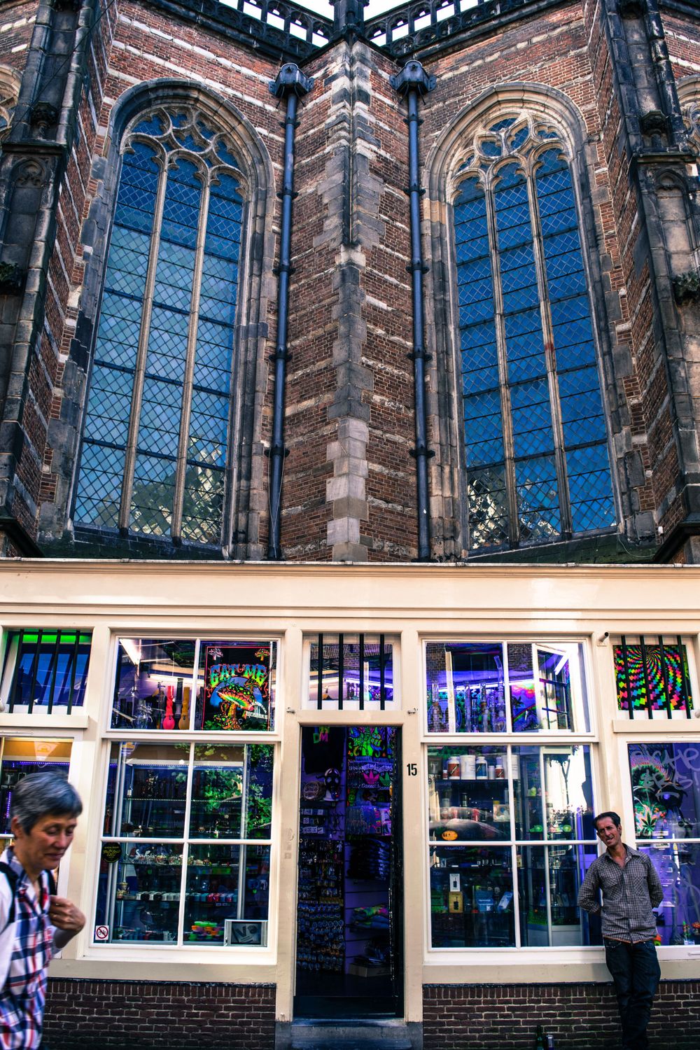 Gothic church windows with colorful shop display below in Amsterdam's historic center.