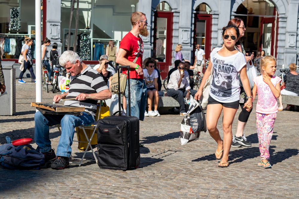 Street performer entertaining passersby on a busy cobblestone street in Amsterdam.