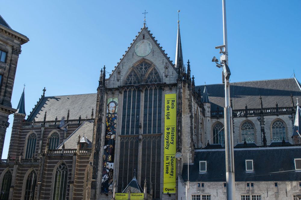 Gothic architecture of Nieuwe Kerk church featuring ornate windows and spires against blue sky.