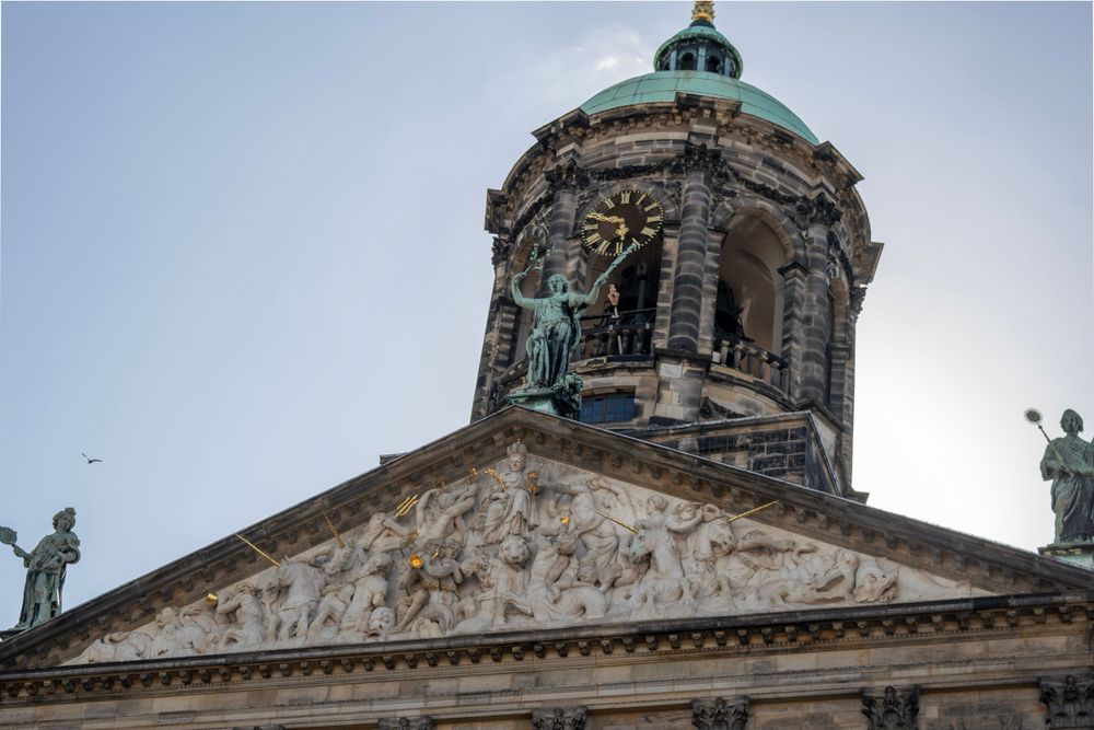 Ornate dome of the Royal Palace in Amsterdam decorated with classical statues and architectural details.