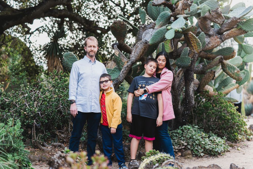 Family group poses together for photo among desert plants and trees.