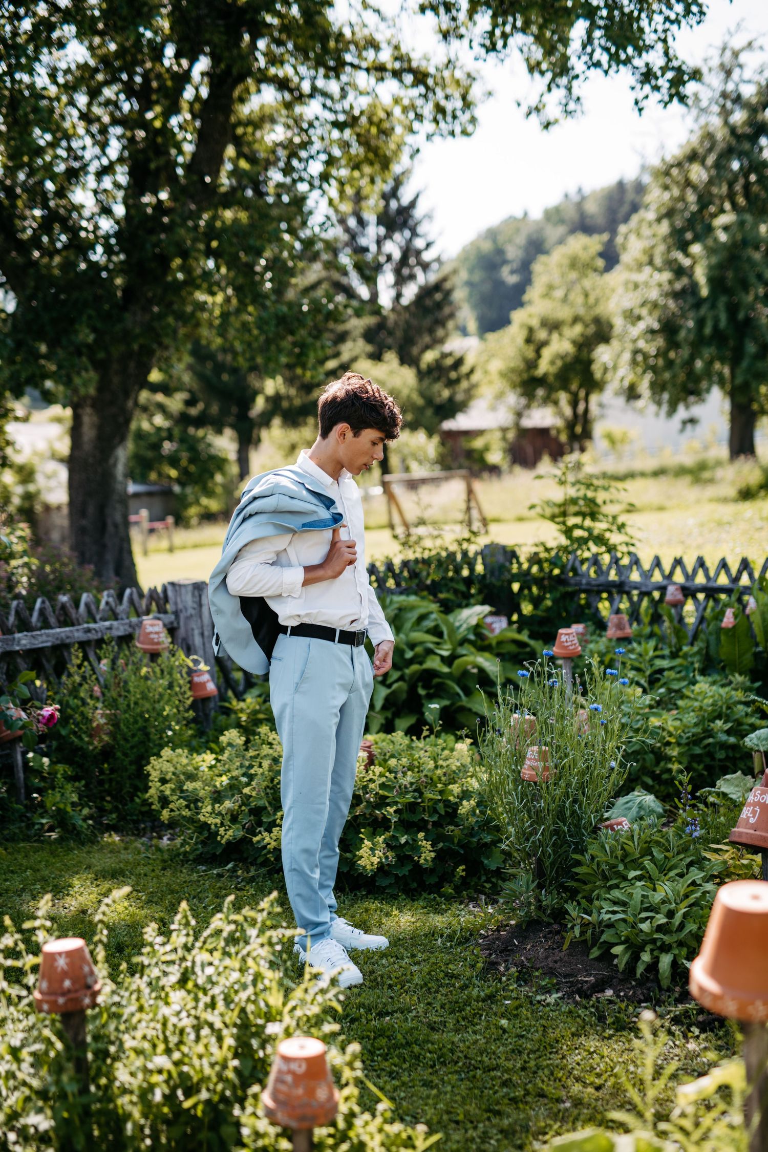 Light-filled garden scene featuring casual attire against a picturesque backdrop of flowers and decorative fencing.