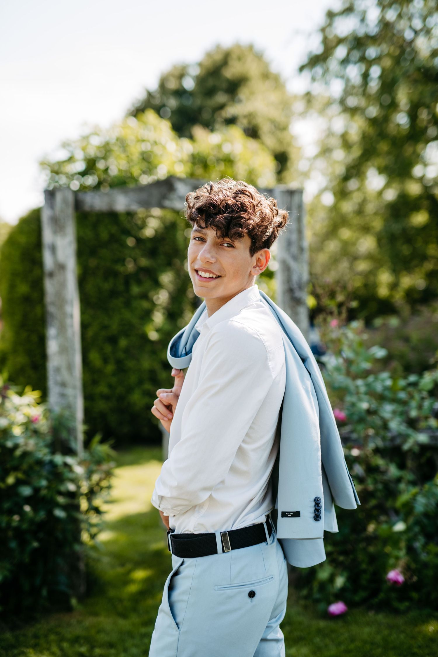 Sunny garden portrait showing a light blue suit and white shirt ensemble.