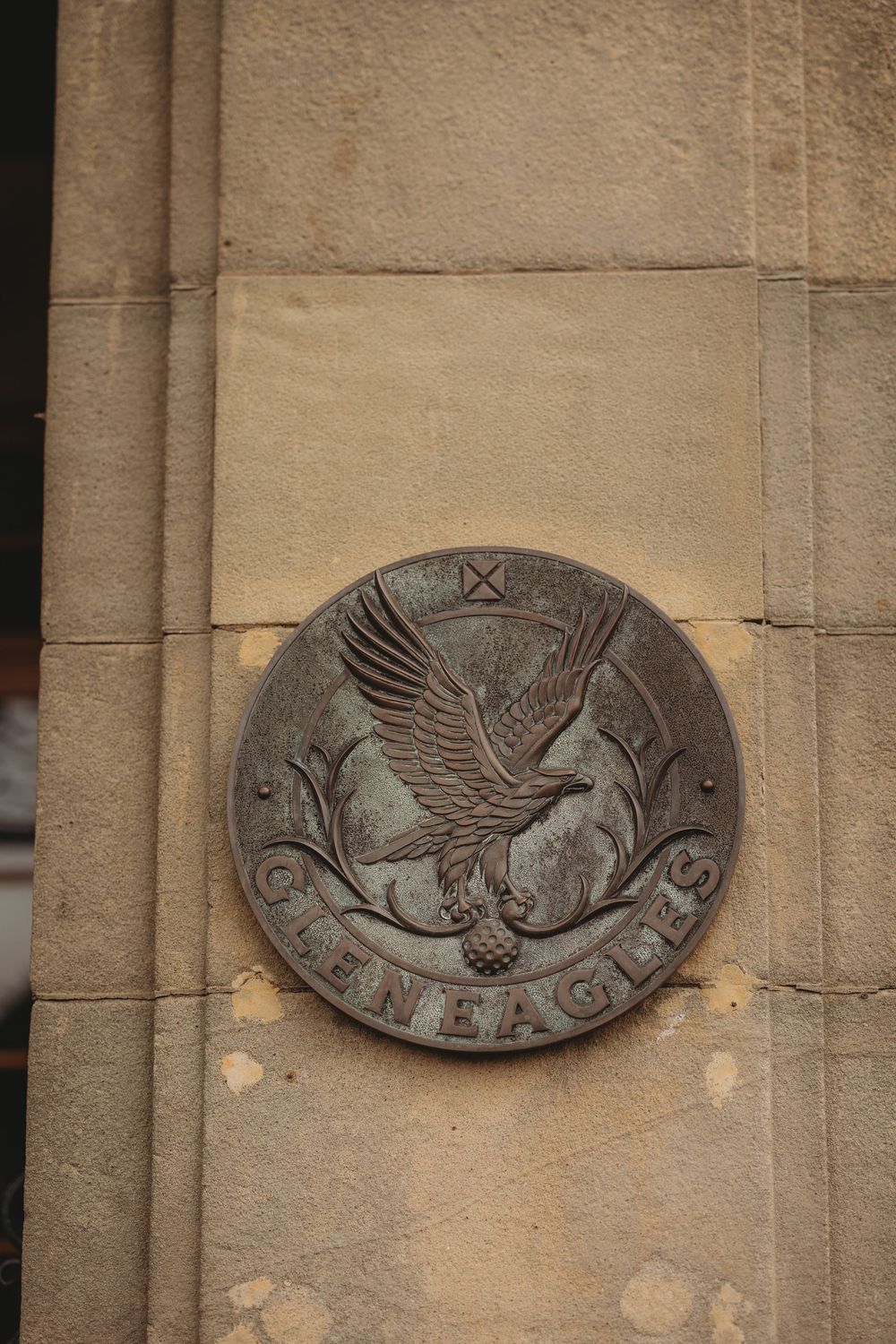 Decorative stone wall plaques featuring carved eagle designs in a row on a beige building exterior.