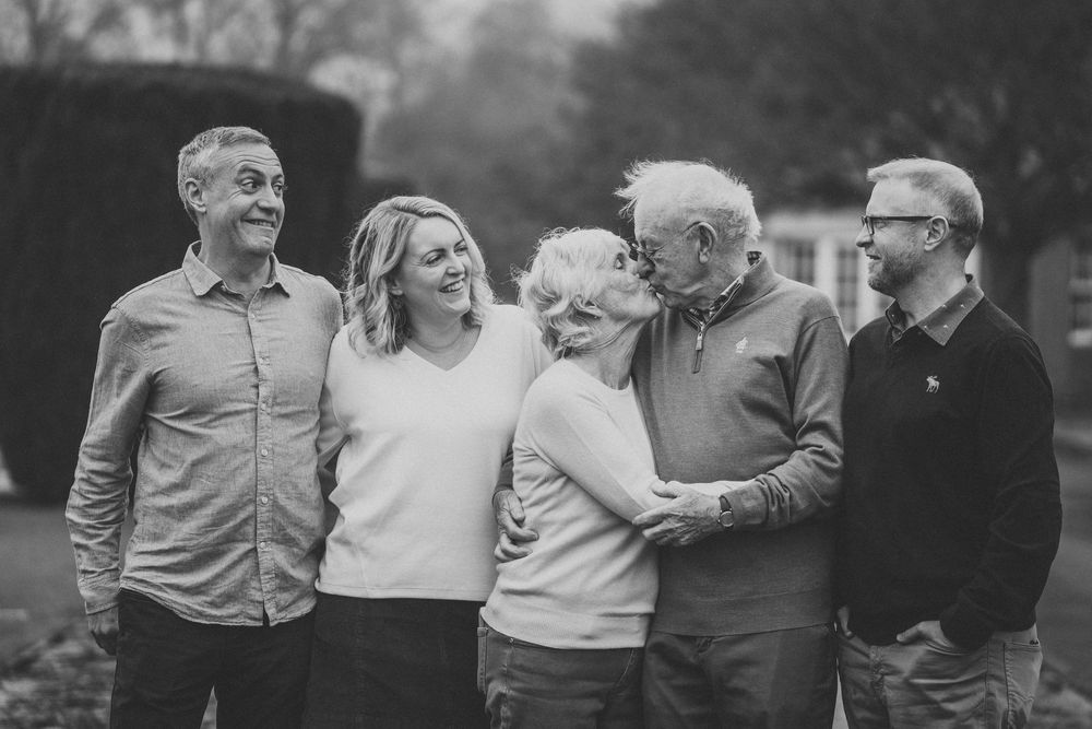 A black and white photo montage showing people embracing and sharing joyful moments outdoors.