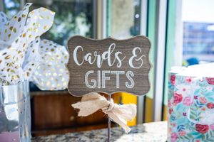 Rustic wooden sign reading 'Cards & Gifts' with decorative bow.