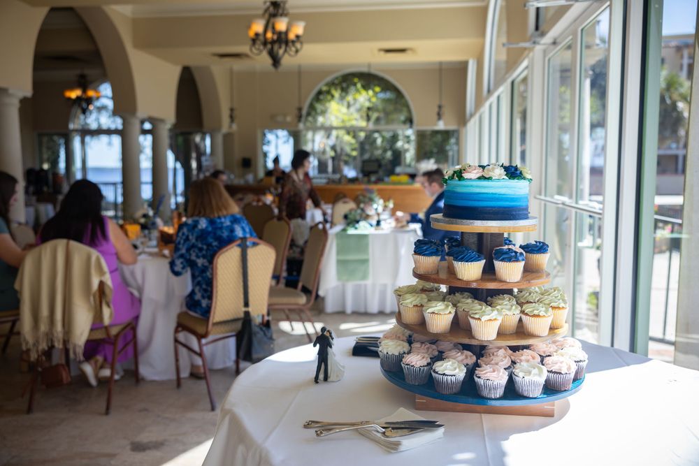 A wedding reception venue with blue-themed dessert display near bright windows.