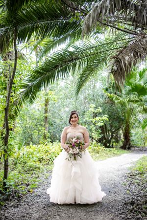 A beautiful white wedding gown against a lush tropical palm forest background.