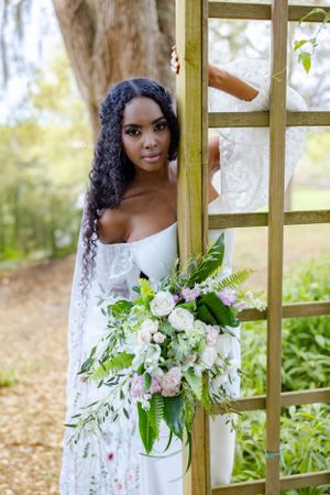 Elegant bridal portrait with white floral bouquet against rustic wooden ladder backdrop.