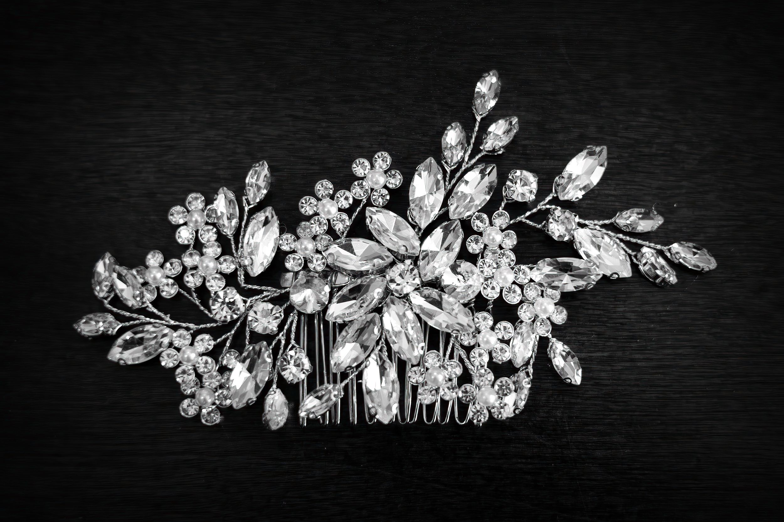 Elegant crystal and pearl floral hair accessory photographed on dark background.