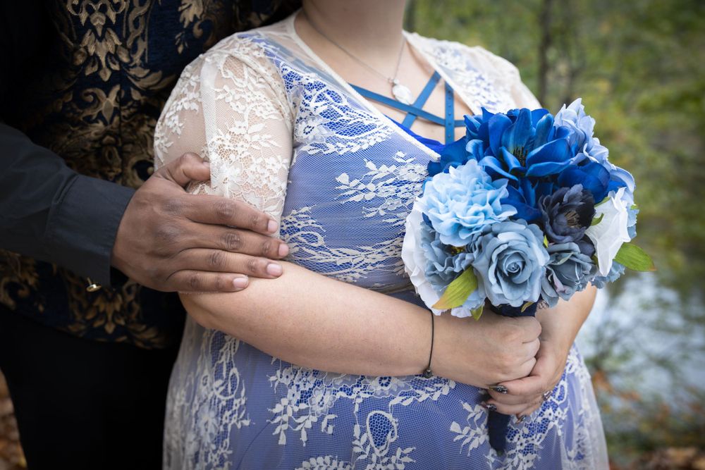 A close-up of blue floral corsage against white lace wedding attire.