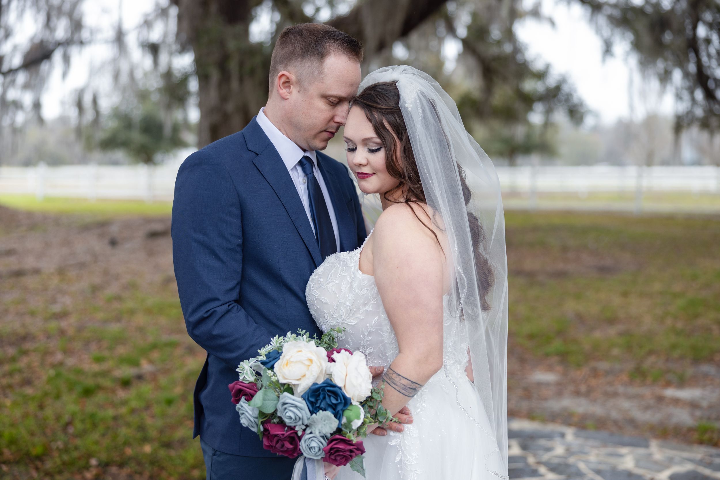 A tender moment between newlyweds beneath Spanish moss draped trees.