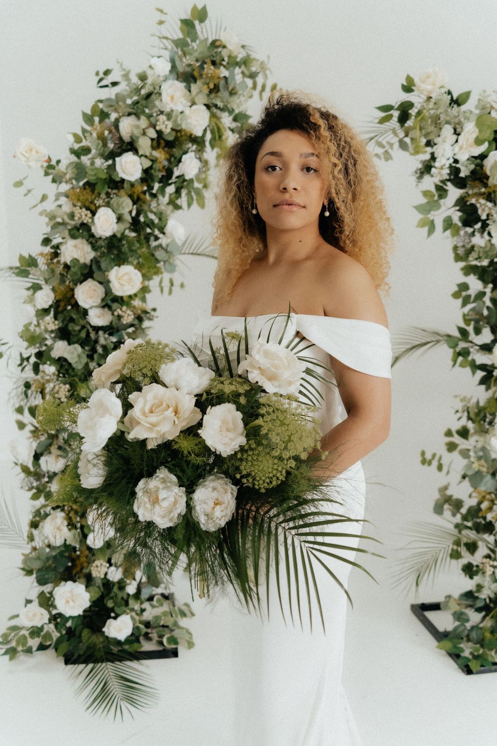 Girl posing elegantly at a bridal show, showcasing a stunning wedding dress with a smile, surrounded by bridal gowns and