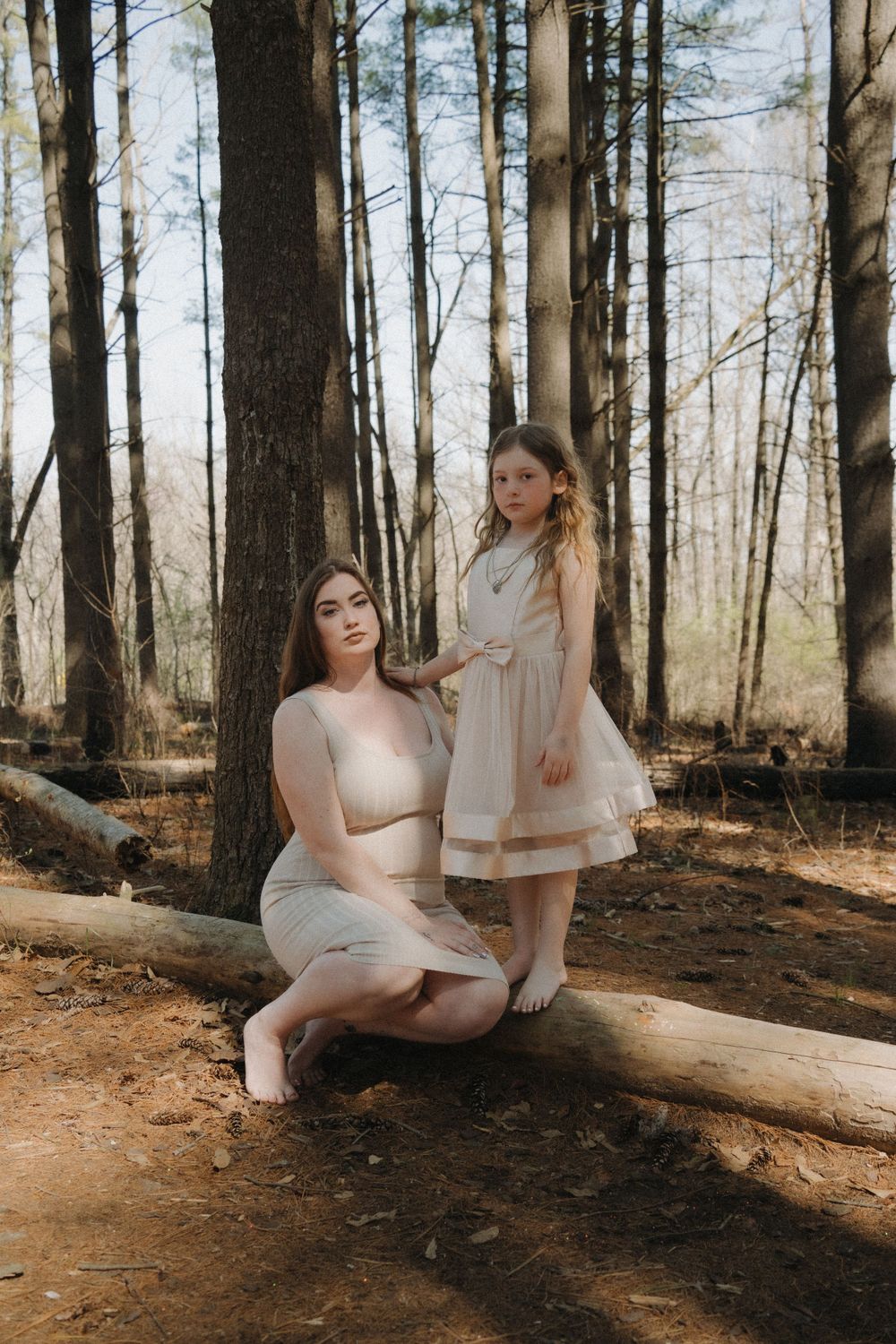 Mom posing with her daughter in the woods at Busch Wildlife, surrounded by tall trees, both smiling and enjoying outdoor