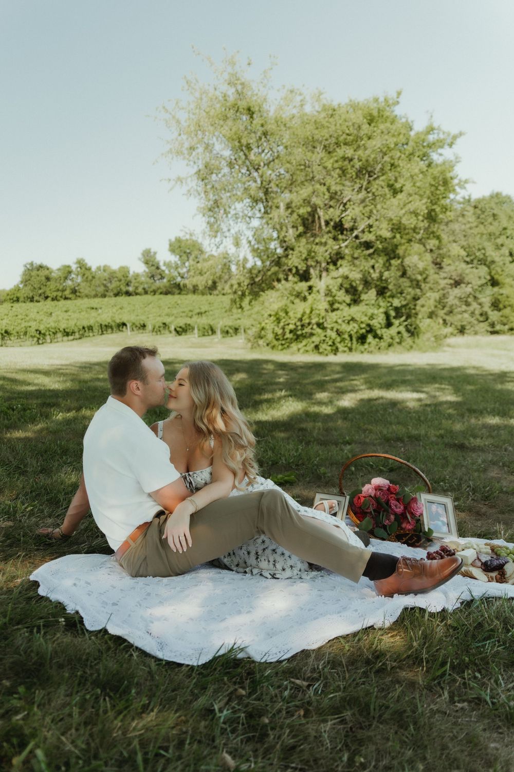 Newly engaged couple sitting on a blanket, gazing into each other’s eyes with a romantic and elegant pose