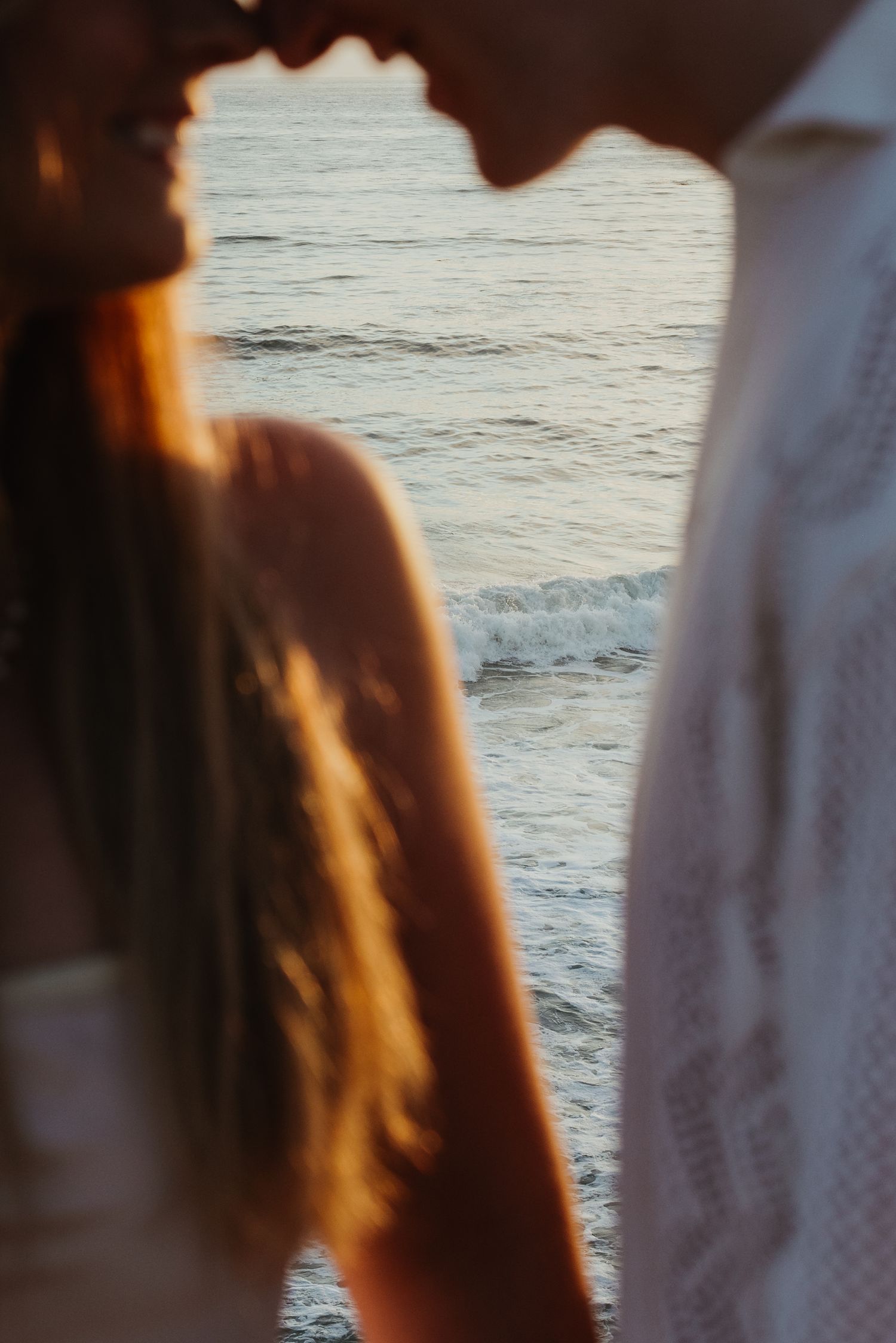An artistic shot of a couple doing eskimo kisses on a beachside cliff in Point Loma California.