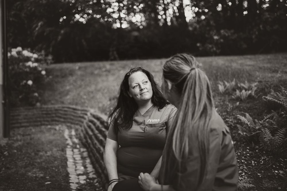 Two people share an intimate moment outdoors in a black and white photograph.