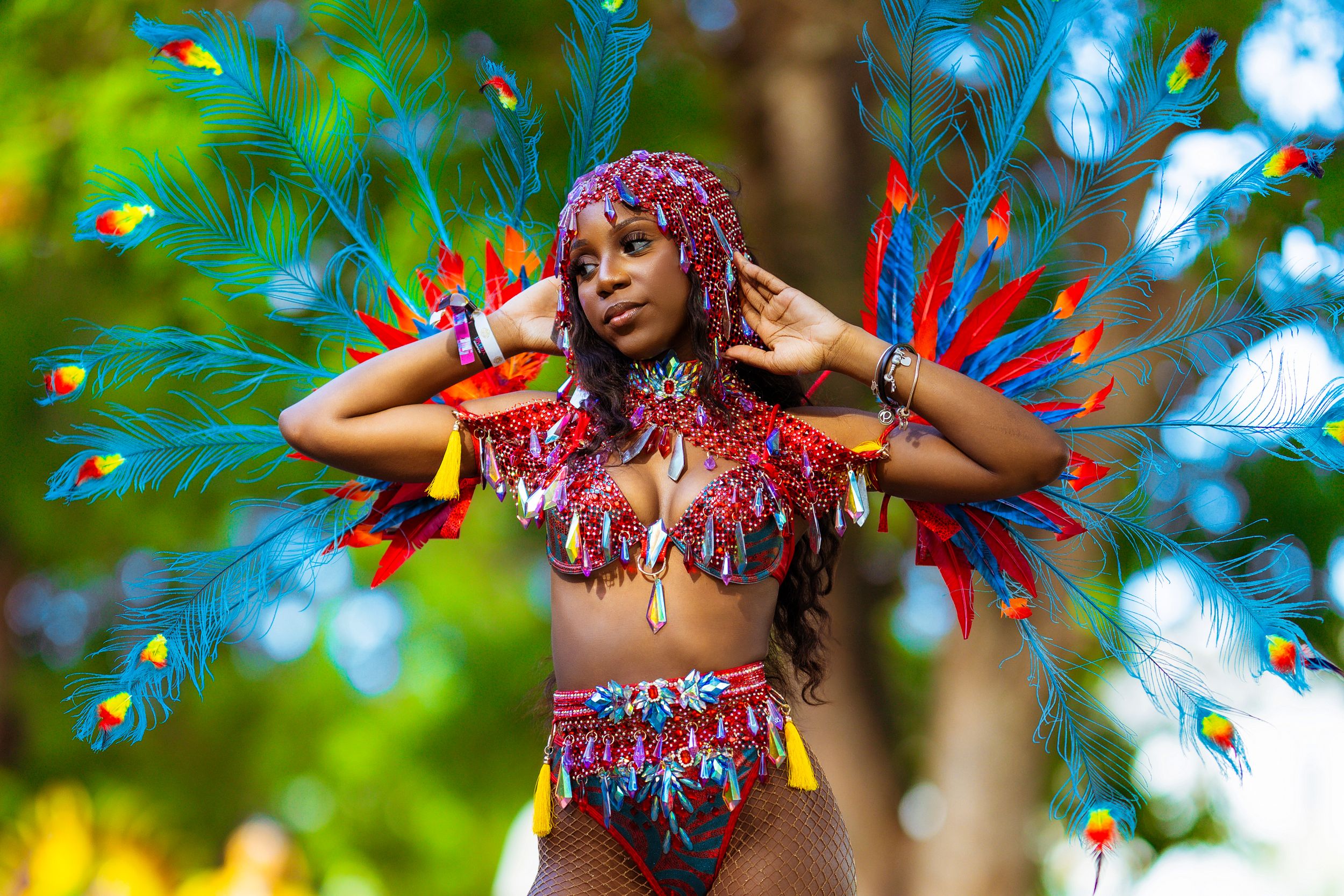 Carnival performer with red and blue feathers — festival editorial portrait by Timoy B Photography.