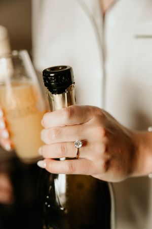 A hand in a white sleeve pours champagne from a dark bottle into a glass in a sequence of four images.