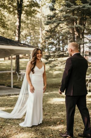 A romantic first look moment between newlyweds in a sunlit outdoor garden setting.