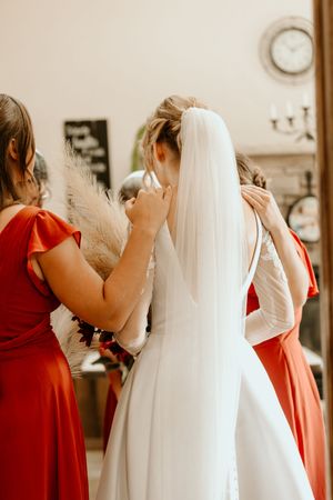 A sequence of wedding preparation photos showing bridesmaids in red dresses helping with a flowing white wedding gown.