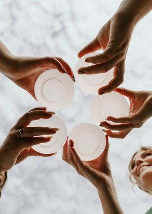 Hands passing a white circular object in a sequence of motion against a light background.