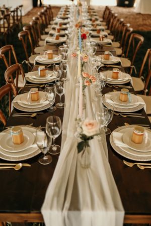 Elegant wedding reception table setting with white linens, place settings and delicate floral centerpieces.