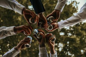 Group of hands forming a circle showing wedding rings in an artistic outdoor photo.