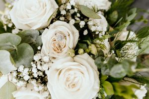 White roses and delicate baby's breath flowers arranged in an elegant wedding bouquet with green foliage.