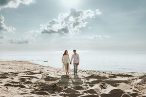 Scenic beachfront panorama with silhouettes against cloudy sky and gentle waves rolling onto shore.