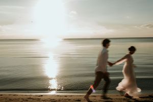 A sequence of beachgoers jumping into calm ocean waters at sunset as light reflects on the serene surface.