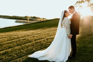 A romantic sunset wedding photo shoot in a golden field with soft backlighting creates an ethereal atmosphere.