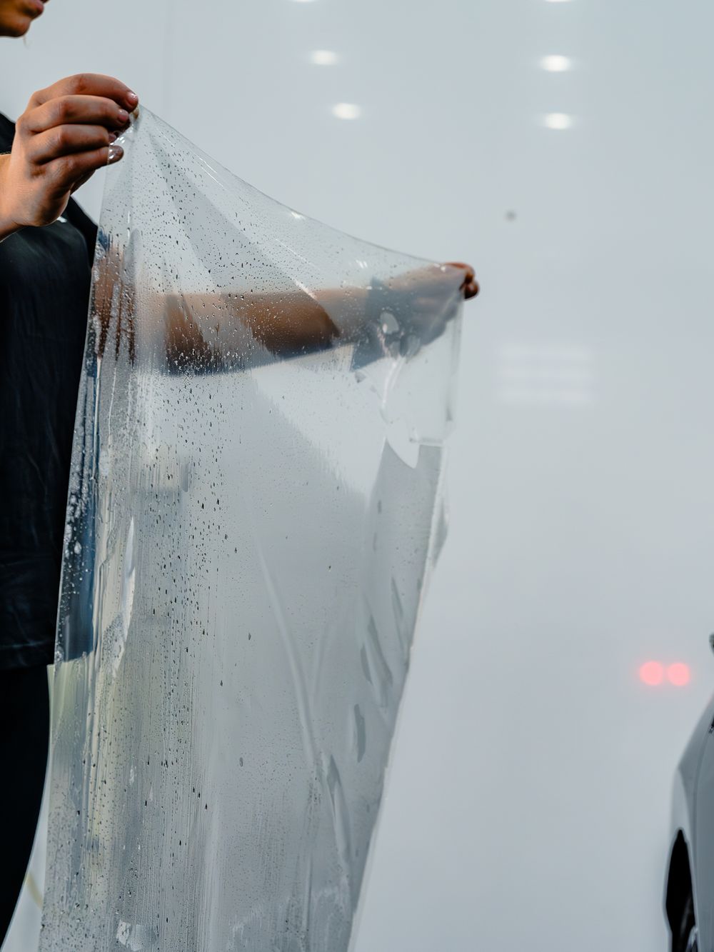 A sequence showing a clear plastic sheet being peeled away from a frosted surface, revealing water droplets and condensation.