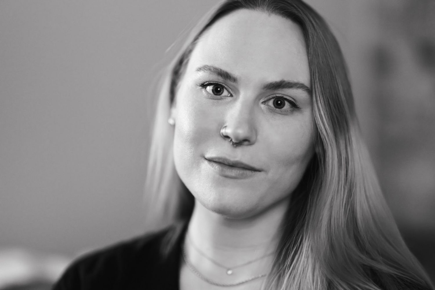 A black and white professional headshot of Emily, a young white woman, with soft lighting and natural expression.