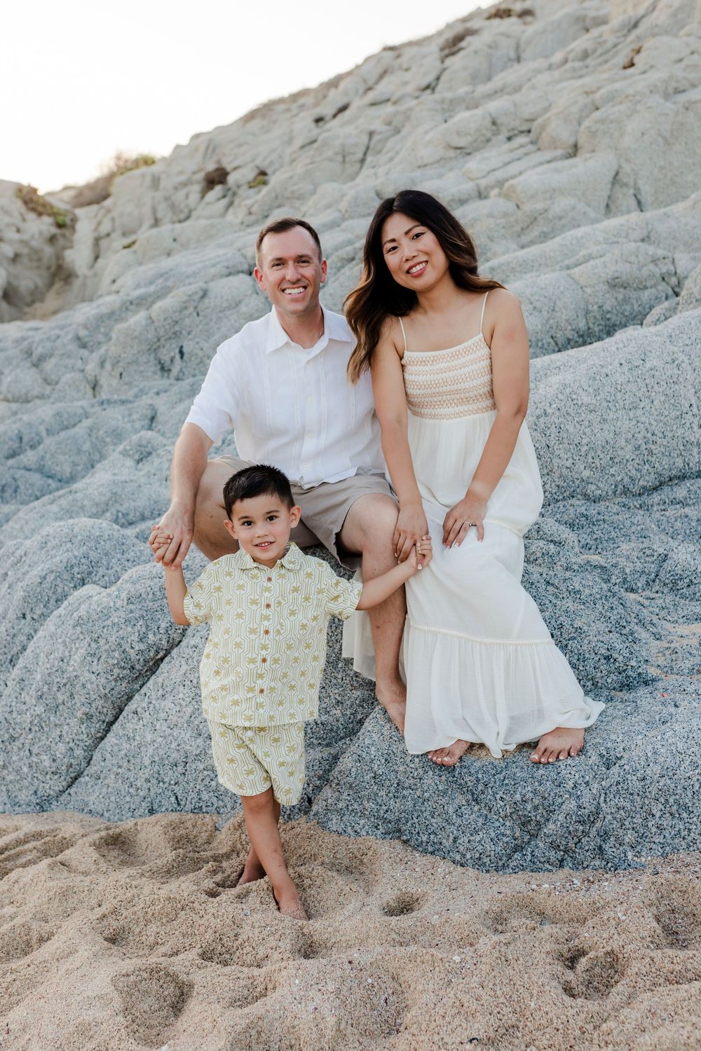 Family sitting together on beach at sunset