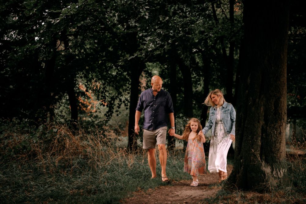 Family walks along a wooded forest path during golden hour on a summer evening.