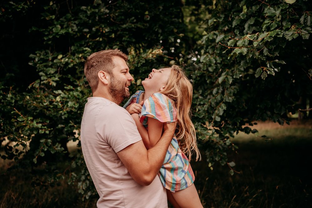 A loving family enjoys tender moments together during an outdoor photo session in a wooded setting.