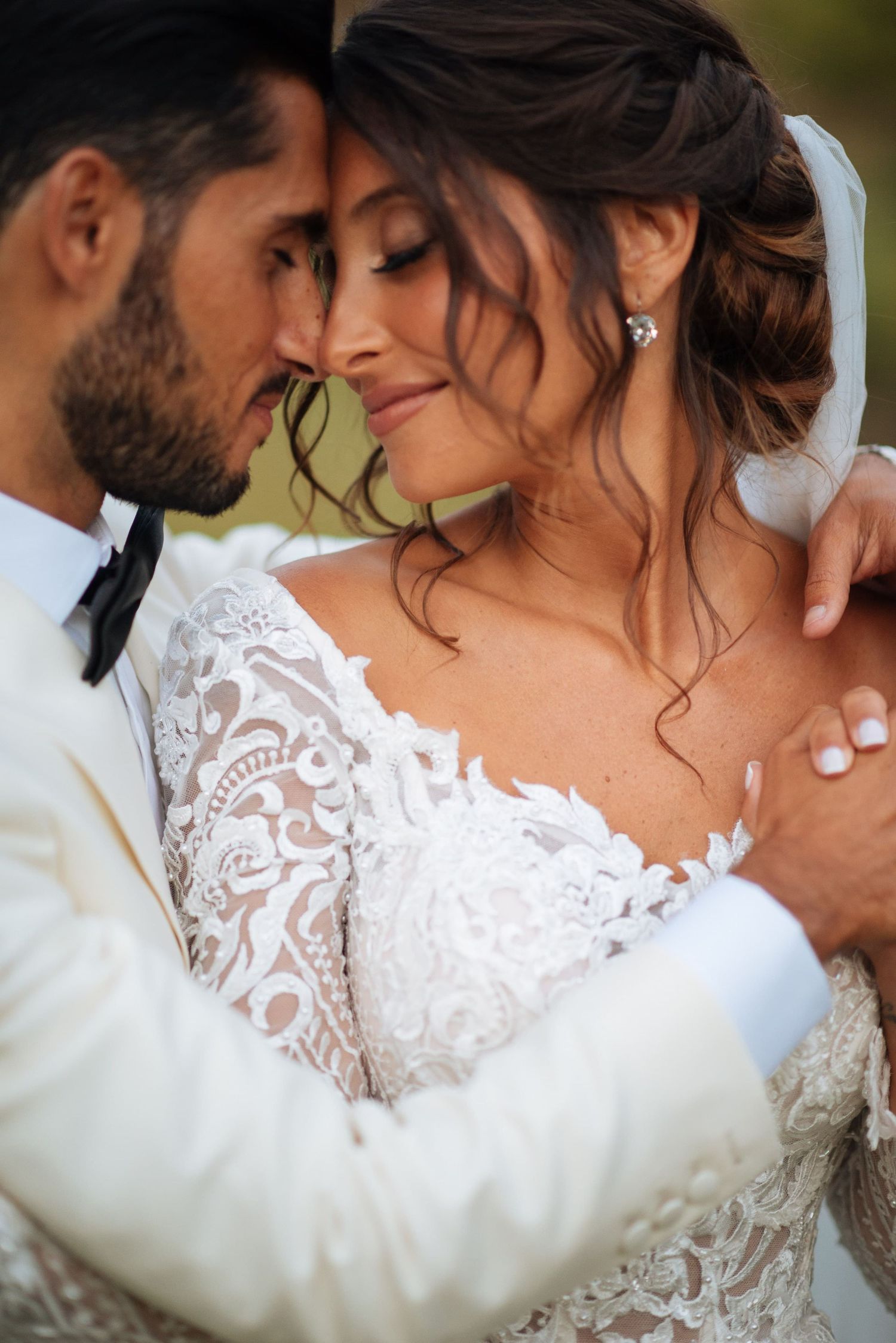 Jeune couple de mariés enlacé, regard complice et lumière douce pour un portrait naturel.