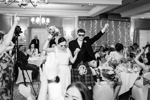 Black and white natural photo of Bride and Groom entering wedding reception at Murrayshall near Perth wearing shades